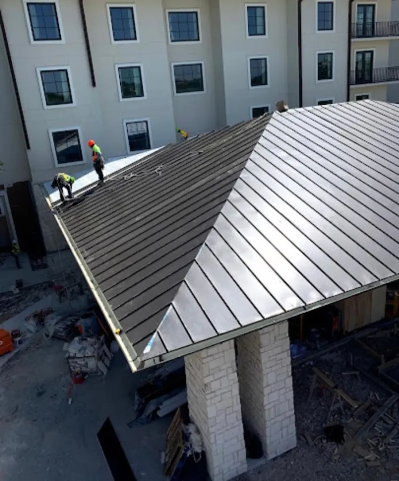 Crew installing standing seam metal roof panels on a commercial project in Thompson